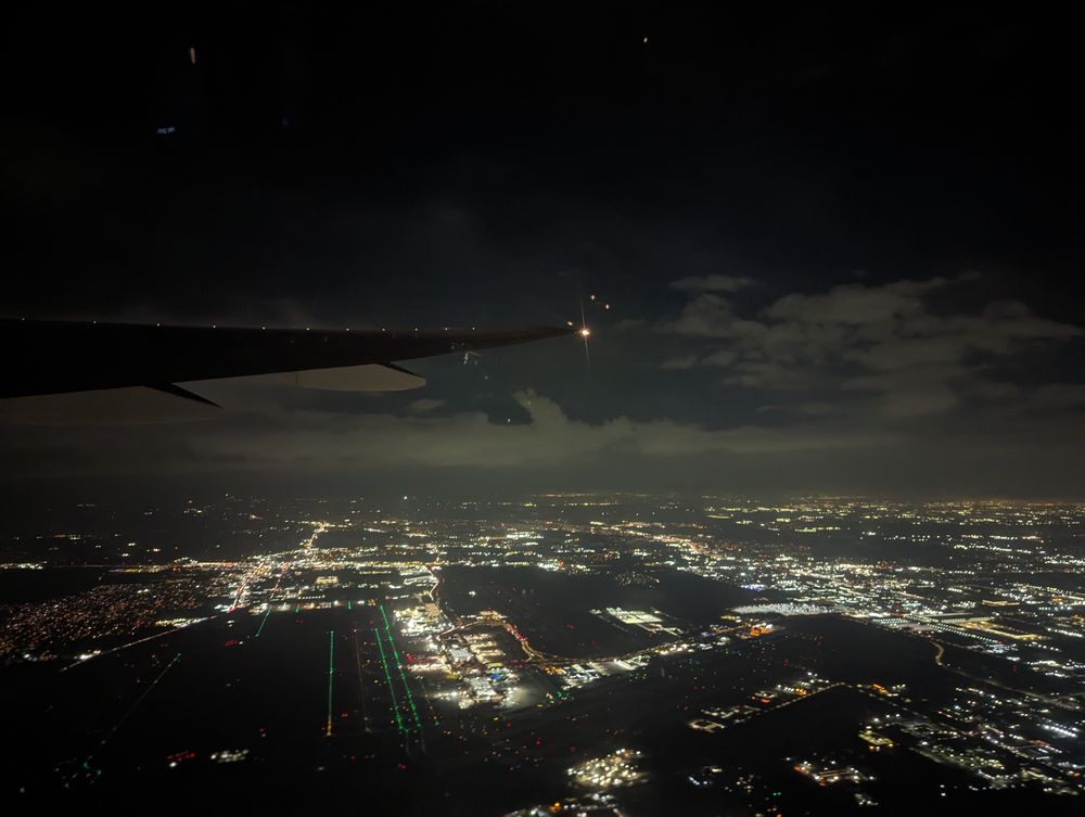 A night photo of city lights from the window of an airplane, possibly Boston, USA